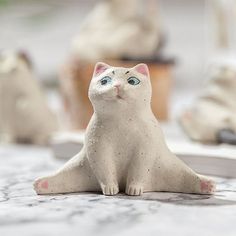 a white cat figurine sitting on top of a table next to other cats