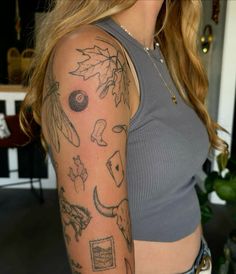 a woman's arm with tattoos on it, including leaves and other things in the background