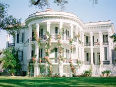 a large white house with flowers on the front and side of it's walls