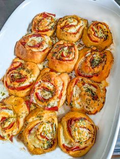 a white platter filled with rolls covered in cheese and toppings