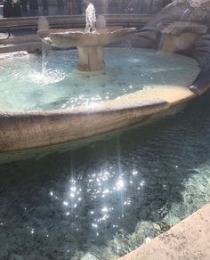 an outdoor fountain with people standing around it