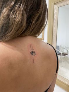 the back of a woman's shoulder with an eye tattoo on her upper arm