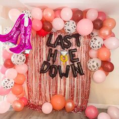 the balloon arch is decorated with pink, orange and white balloons that say last down