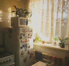 a refrigerator with magnets on it next to a window and a table in front of it