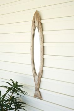 an oval mirror hanging on the side of a white wall next to a potted plant