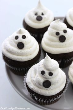 cupcakes with white frosting and chocolate chips decorated as ghost faces on a plate