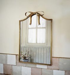 a bathroom mirror sitting on top of a tiled wall