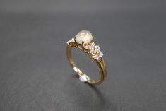 a close up of a gold ring with pearls and diamonds on the side, sitting on a gray surface