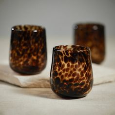 three brown glass cups sitting on top of a white cloth