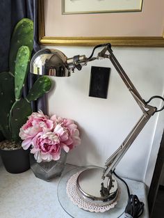 a desk lamp sitting on top of a table next to a potted plant