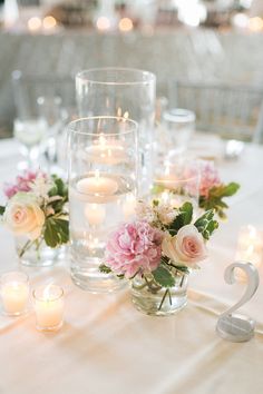 the table is set with candles and flowers in glass vases, which are on top of each other