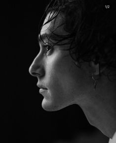 a black and white photo of a man with curly hair looking off to the side