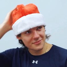 a young man wearing a red and white santa's hat with his hands on his head