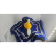 a crocheted blue and white blanket with a yellow ball on it's end