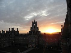 the sun is setting over an old building