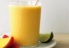 a smoothie in a glass with a straw next to an apple and lime slice