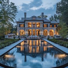 a large house with a pool in front of it at night, surrounded by trees and bushes