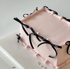 a pink cake with black ribbon and bow decorations