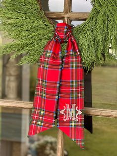 a christmas wreath hanging on the side of a wooden window sill in front of a house