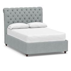 a bed with a tufted headboard and white sheets on it's sides