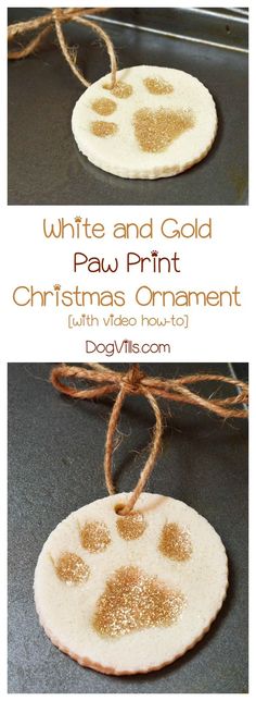 a white and gold paw print christmas ornament hanging from twine on a table