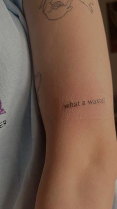 a person with a tattoo on their arm that says, what is a waste?