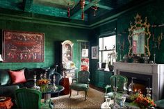 a living room with green walls and furniture in the center, along with paintings on the wall