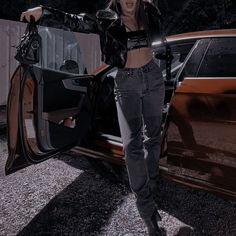 a woman standing next to a brown car