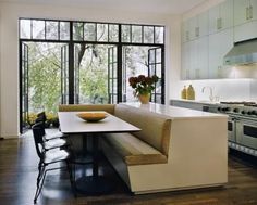 a kitchen with a table and chairs next to a window that looks out onto the woods