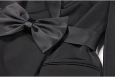 Brooke Black Bow Mini Blazer Dress for Women - Slim Fit Our Ladies' Suit Dress is made with a pointed collar, waist belt, and a large butterfly bow, all crafted from luxurious faux silk satin fabric, while the main body is constructed with a sturdy suit fabric. With a length that falls below the hips, this dress can be worn as a stylish outerwear piece or as a skirt, making it a versatile addition to your wardrobe. The tailored fit highlights the feminine silhouette, and the waist belt cinches a Elegant Fitted Dress With Bow Tie, Formal Black Dress With Detachable Bow, Black Bow Tie Evening Dress, Black Satin Dress With Satin Bow, Elegant Evening Dresses With Bow Tie, Black Silk Dress With Bow, Elegant Office Dress With Bow Detail, Classic Formal Dress With Bow, Elegant Fitted Dress With Ribbon