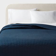 a bed with white pillows and blue bedspread on top of the headboard