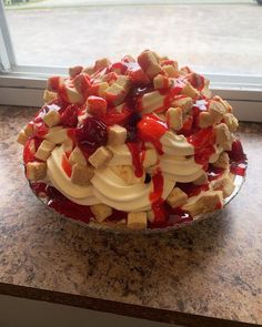 a pie with strawberries, bananas and cream on it sitting on a counter next to a window