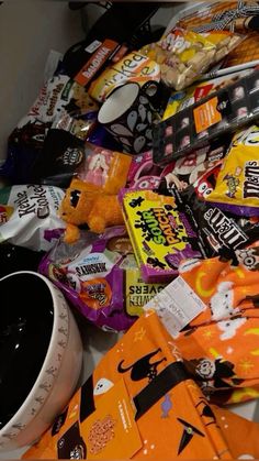 a pile of halloween candy and snacks on a table with a stuffed animal next to it