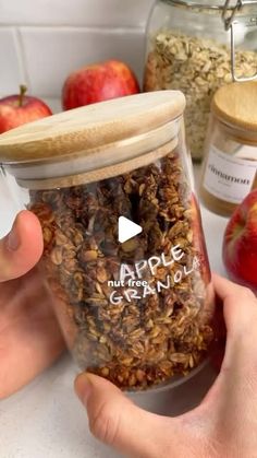 a person holding an apple and granola jar