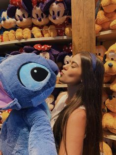 a woman is kissing a stuffed animal in front of shelves with teddy bears and other stuffed animals