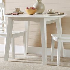 a white table with two chairs and a bowl of fruit on the plate next to it