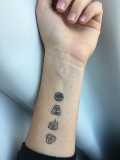 a woman's arm with a small tattoo on the wrist and four different objects