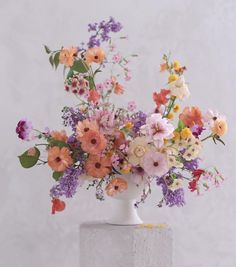 a white vase filled with lots of colorful flowers