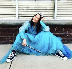 a woman in a blue dress sitting on the ground