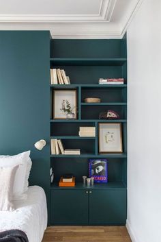 a bed sitting in a bedroom next to a green book shelf with books on it