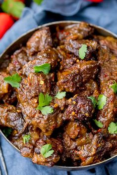 a bowl filled with meat and garnished with cilantro on the side