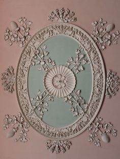 an ornate ceiling medallion in the center of a room with pink walls and white trim