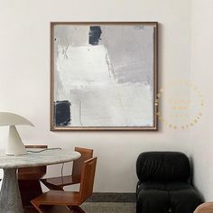 a painting hanging on the wall above a table with chairs and a lamp in front of it