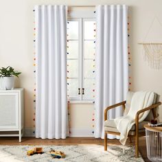 a living room with white curtains and colorful polka dot trimmings on the window