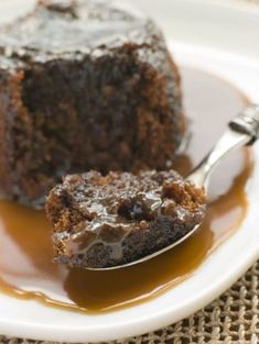 a piece of chocolate cake on a white plate with caramel sauce and a spoon