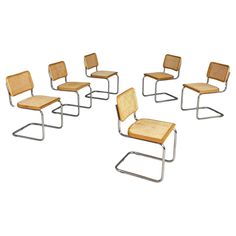 six chairs with woven seats on each side and one chair in the middle, all facing different directions