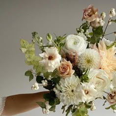 a woman holding a bouquet of flowers in her hand with white and pink blooms on it