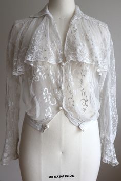 A 1900s tan lace blouse. All-tulle lace that is soft and smooth to the touch. The beautiful hand embroidery of plants is captivating. The large collar-like yoke is attractive, and the silhouette looks great from any angle. The front closes with decorative crochet buttons and hooks. Snap closure at the cuffs. Gently hand-washed. Small when closed at the bottom waist, but also looks great open. Approximately S size. Flat measurements Shoulder width 15.3 (39 cm) Bust 19.6 (50 cm) Waist width (hem w Formal Sheer Lace Top, Lace Wedding Top With Lace Collar, Elegant Lace Top For Day, Victorian Lace Blouse With Lace Trim, Vintage Lace Top With Ruffles, Victorian Style Formal Top With Lace Collar, Victorian Lace Blouse For Daywear, Classic Lace Top With Lace Collar, Feminine Lace Top With Lace Cuffs For Wedding