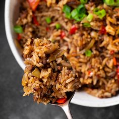 a close up of a spoon with rice and vegetables in it on a table top