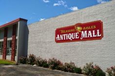 a sign on the side of a building that says antique mall in front of it